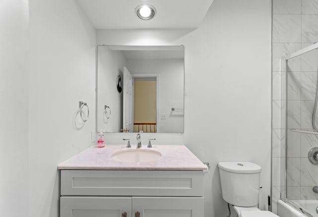 bathroom featuring toilet, combined bath / shower with glass door, and vanity