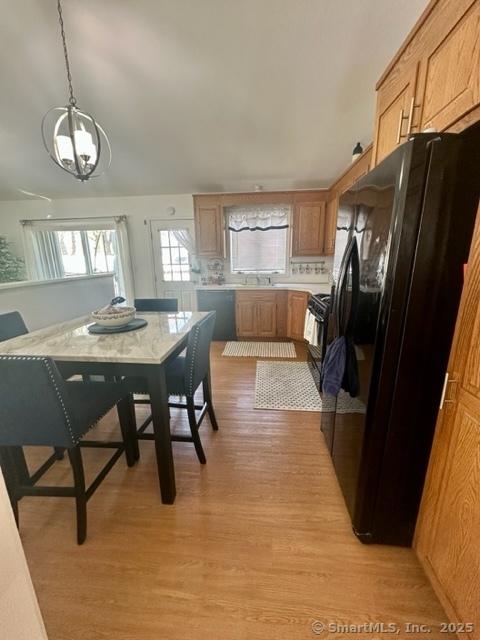 kitchen with a notable chandelier, light hardwood / wood-style flooring, hanging light fixtures, and black appliances