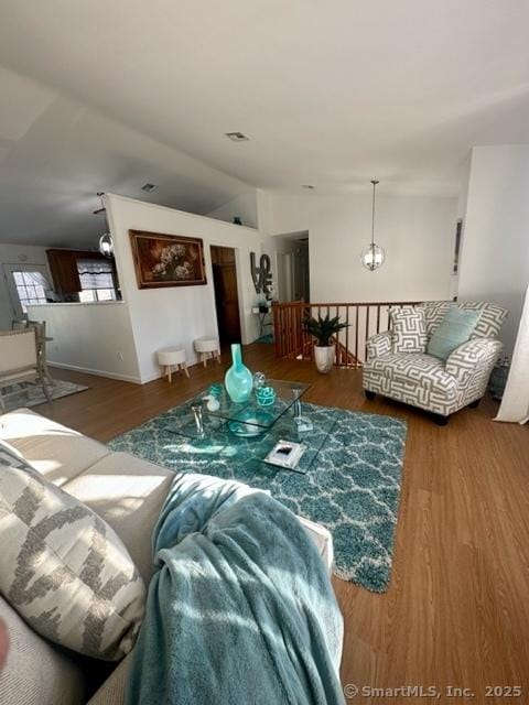 living room featuring hardwood / wood-style flooring, lofted ceiling, and a notable chandelier