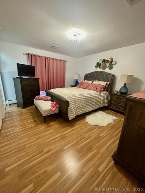 bedroom with light hardwood / wood-style flooring and baseboard heating