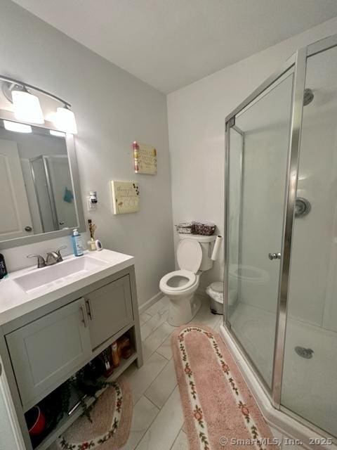 bathroom with a shower with door, vanity, and toilet