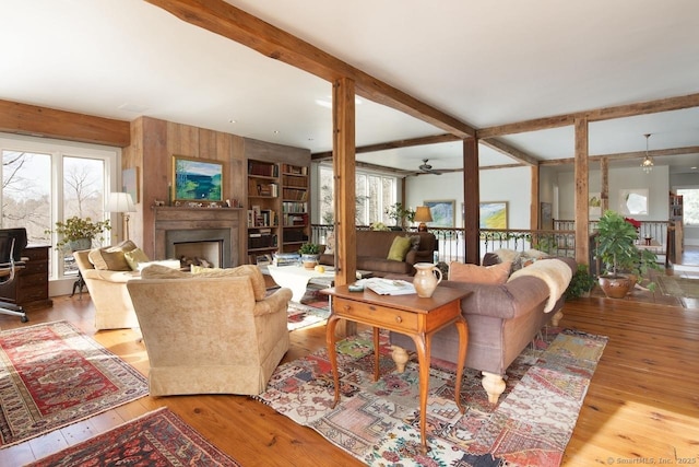 living room featuring a healthy amount of sunlight, wood walls, beamed ceiling, and light wood-type flooring