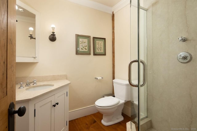 bathroom with toilet, wood-type flooring, ornamental molding, vanity, and a shower with door