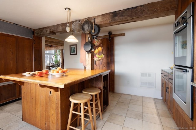 kitchen featuring pendant lighting, butcher block countertops, a breakfast bar area, double oven, and a barn door