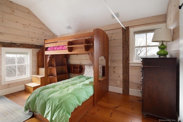 bedroom featuring hardwood / wood-style flooring, lofted ceiling, and wood walls