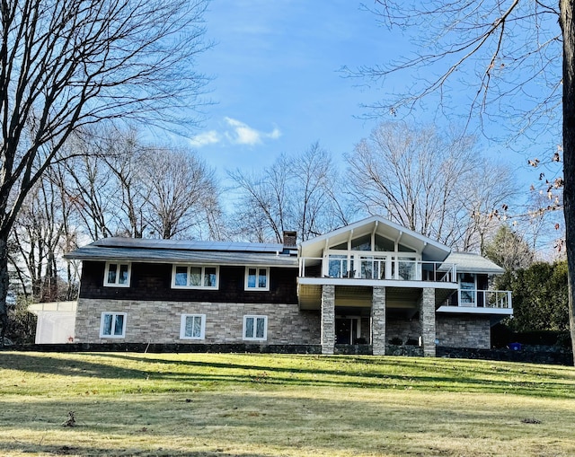 view of front of house with a chimney, a front yard, and a balcony