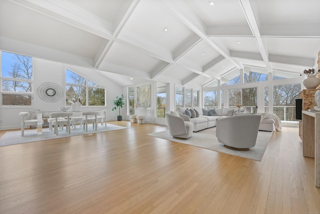 living area with a healthy amount of sunlight, light wood-style floors, vaulted ceiling with beams, and a fireplace