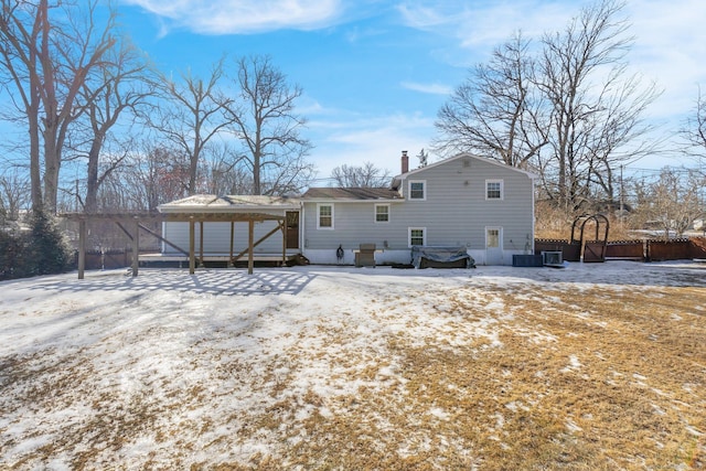 snow covered rear of property featuring central AC