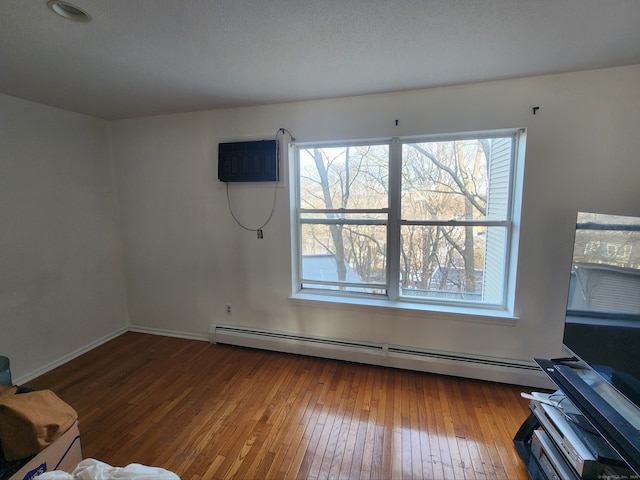 unfurnished living room featuring hardwood / wood-style flooring, a baseboard radiator, and a wall mounted AC