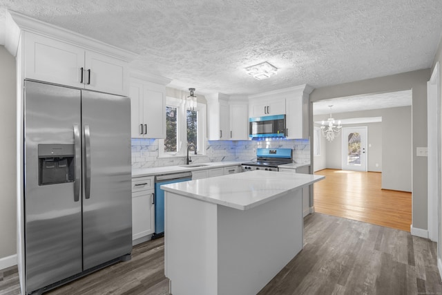 kitchen featuring pendant lighting, appliances with stainless steel finishes, white cabinetry, dark hardwood / wood-style floors, and a kitchen island