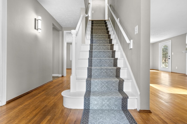 stairs with hardwood / wood-style flooring and a textured ceiling