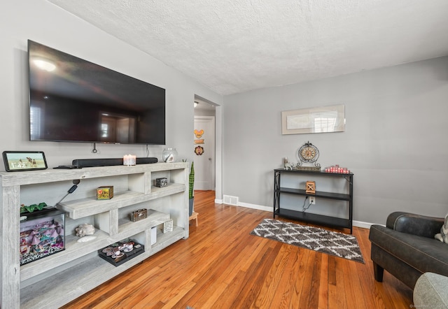 living room with a textured ceiling and light hardwood / wood-style floors