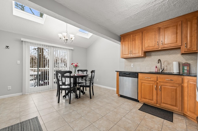 kitchen with tasteful backsplash, stainless steel dishwasher, decorative light fixtures, sink, and lofted ceiling with skylight