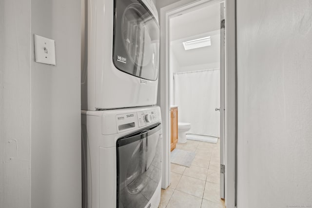 laundry room with stacked washing maching and dryer and light tile patterned floors