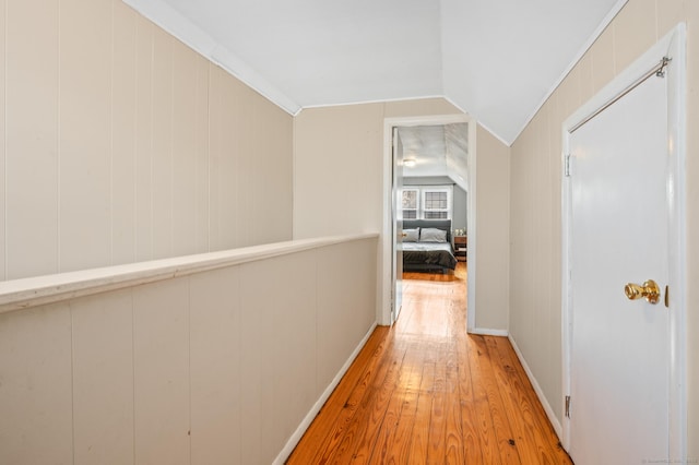 hall featuring light wood-type flooring and vaulted ceiling