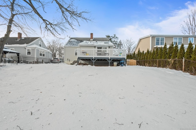 snow covered back of property with a wooden deck