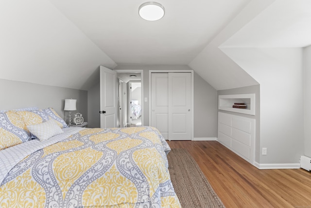 bedroom with a closet, lofted ceiling, and light hardwood / wood-style flooring