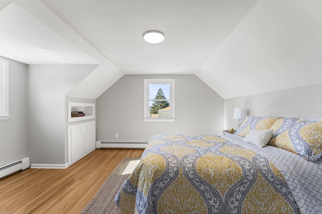 bedroom with a baseboard heating unit, vaulted ceiling, and light wood-type flooring