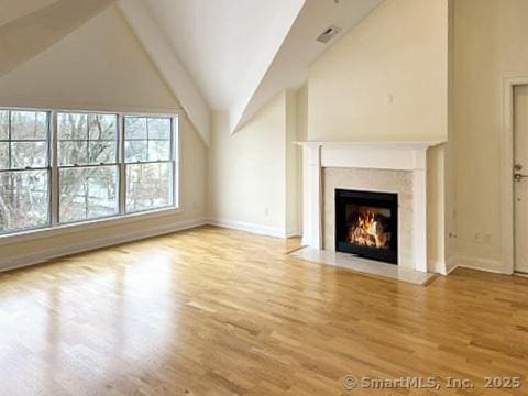 unfurnished living room featuring high vaulted ceiling and light hardwood / wood-style floors