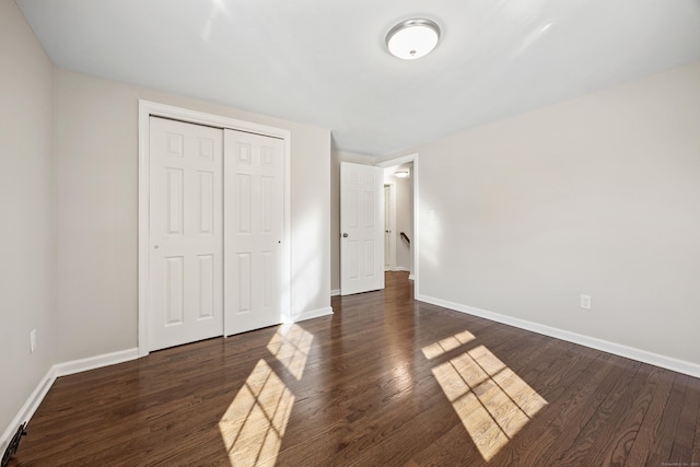 unfurnished bedroom with dark hardwood / wood-style floors and a closet