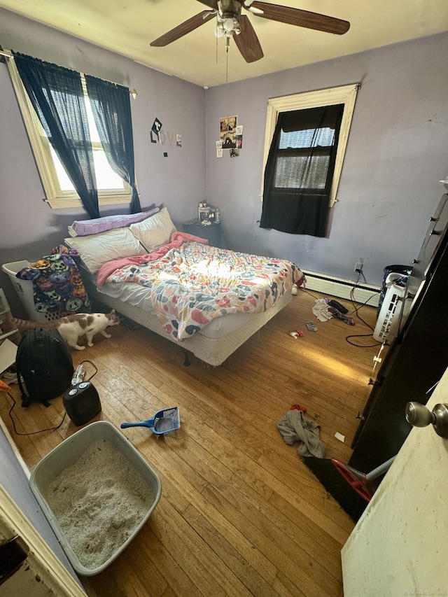 bedroom with hardwood / wood-style floors, a baseboard radiator, and ceiling fan