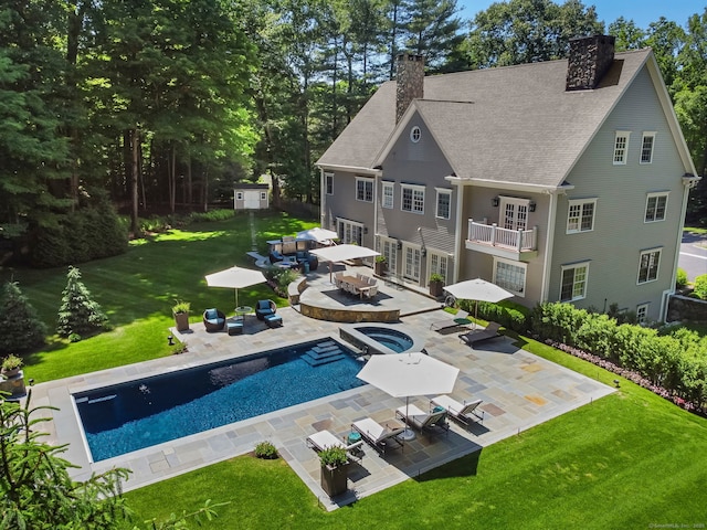 back of property with a lawn, a balcony, a chimney, and a patio area