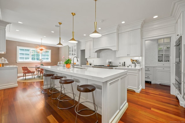 kitchen featuring premium range hood, dark wood finished floors, light countertops, white cabinets, and a sink