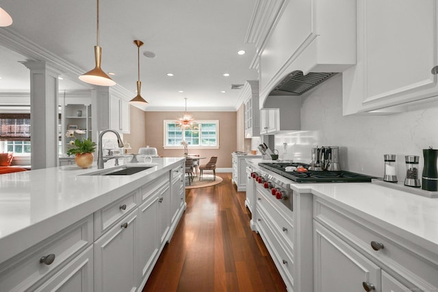 kitchen featuring stainless steel gas cooktop, a sink, light countertops, custom range hood, and crown molding