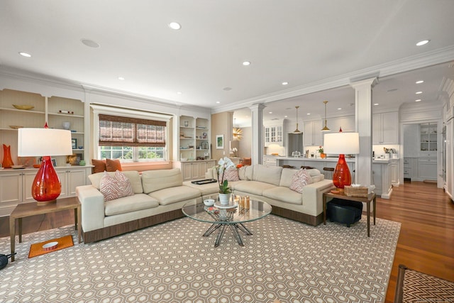 living room with decorative columns, wood finished floors, recessed lighting, and ornamental molding