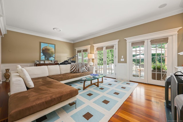 living room featuring a wainscoted wall, ornamental molding, french doors, and wood finished floors