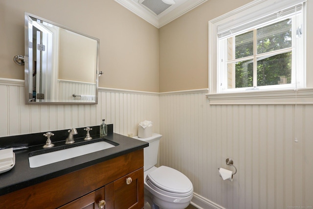 half bathroom featuring visible vents, a wainscoted wall, toilet, ornamental molding, and vanity