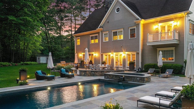 rear view of house with a patio, a balcony, an outdoor fire pit, an outdoor structure, and a storage shed