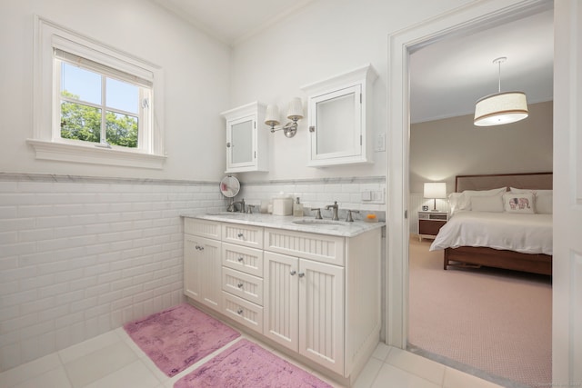 ensuite bathroom featuring a wainscoted wall, a sink, ensuite bath, tile walls, and crown molding