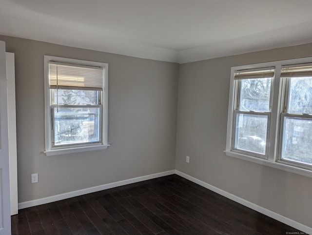 empty room featuring dark wood-type flooring and plenty of natural light