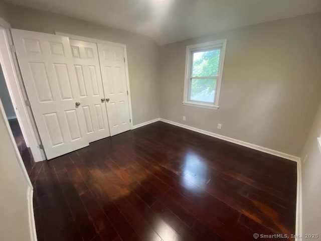 unfurnished bedroom featuring dark hardwood / wood-style floors and a closet