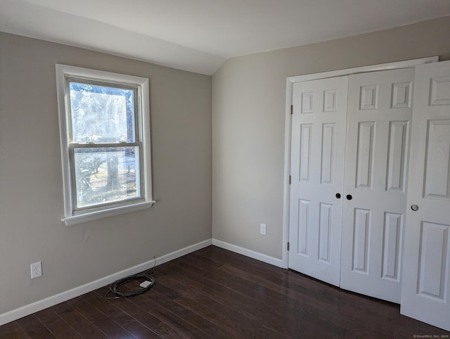 unfurnished bedroom with vaulted ceiling, dark wood-type flooring, and a closet