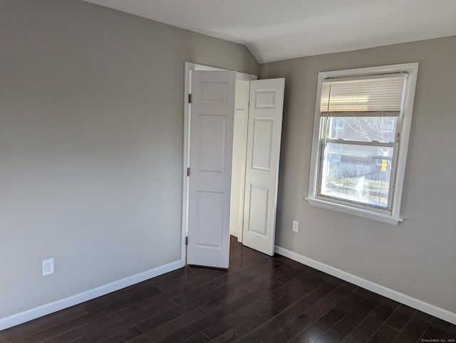 unfurnished bedroom with dark hardwood / wood-style flooring and vaulted ceiling