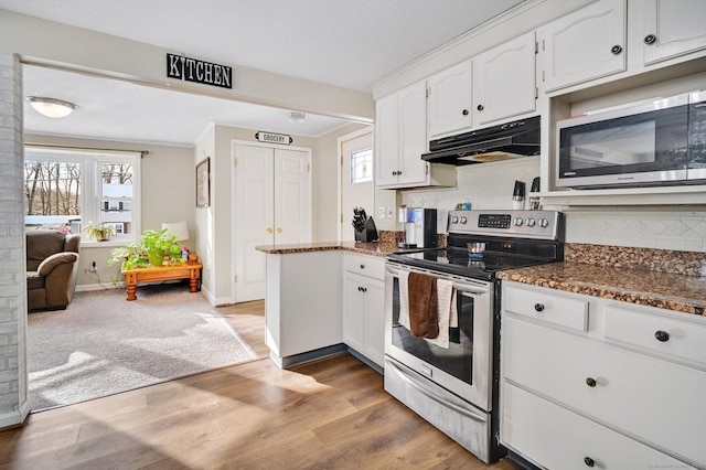 kitchen with white cabinetry, stainless steel appliances, a wealth of natural light, and dark stone counters