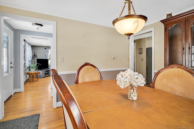 dining space featuring crown molding, a wealth of natural light, and light wood-type flooring