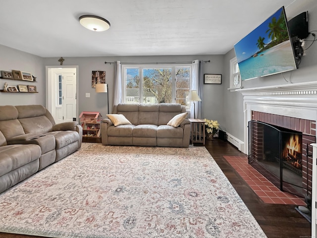 living room with a baseboard radiator, a brick fireplace, and dark hardwood / wood-style floors