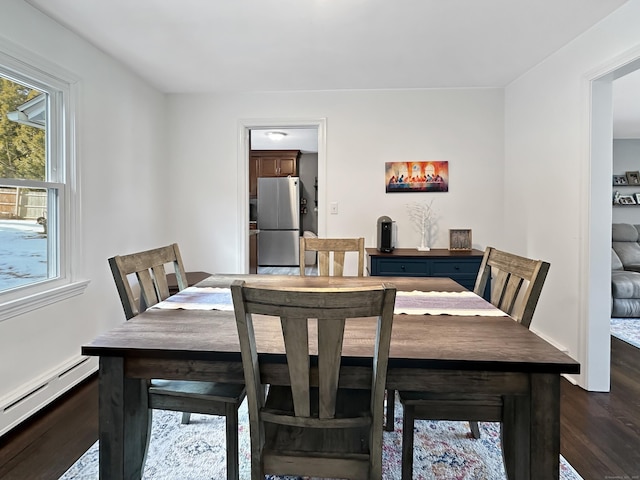 dining space featuring a baseboard heating unit, a wealth of natural light, and dark hardwood / wood-style floors