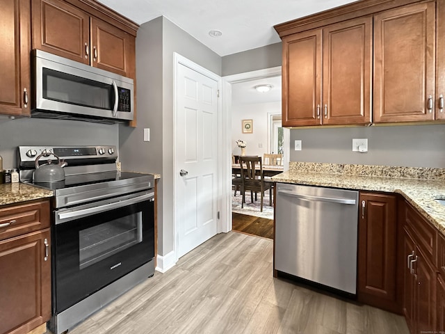 kitchen featuring stainless steel appliances, light stone countertops, and light hardwood / wood-style flooring