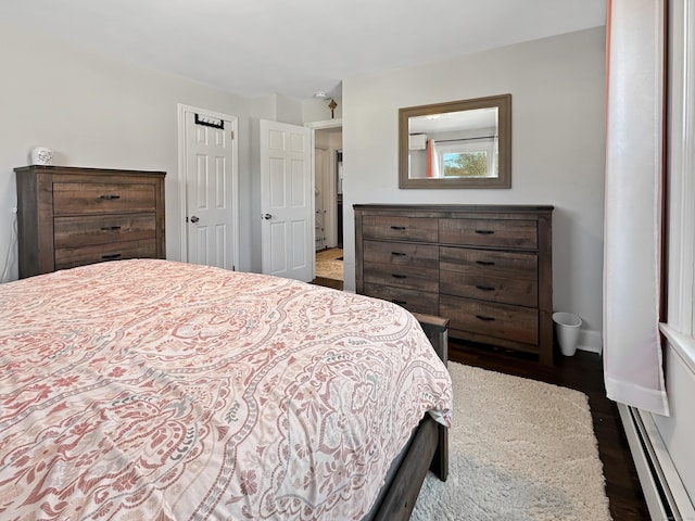 bedroom featuring baseboard heating and dark hardwood / wood-style floors