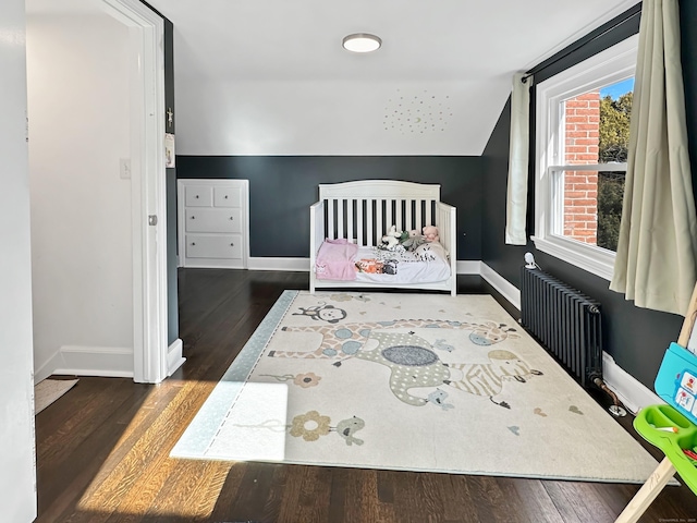 bedroom featuring dark hardwood / wood-style flooring, radiator heating unit, and lofted ceiling