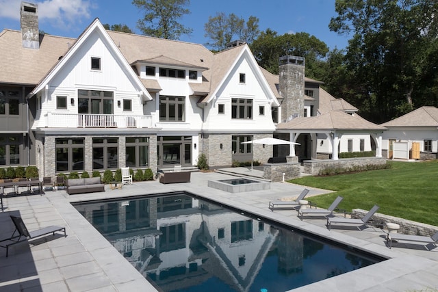 back of house featuring an outdoor pool, a patio, a balcony, a jacuzzi, and an outdoor hangout area