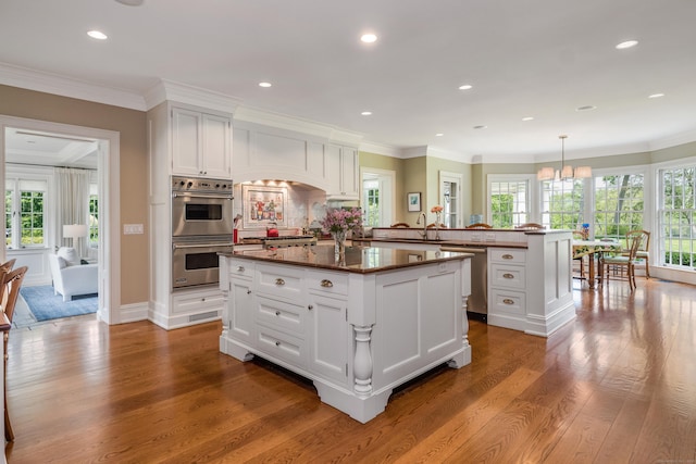 109 Elys Ferry Rd, Lyme, CT 06371 - kitchen with appliances with stainless steel finishes, wood finished floors, dark countertops, a peninsula, and a kitchen island
