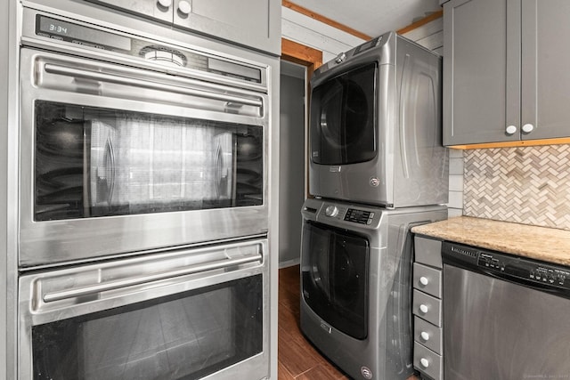 laundry room featuring stacked washer / drying machine and dark hardwood / wood-style flooring