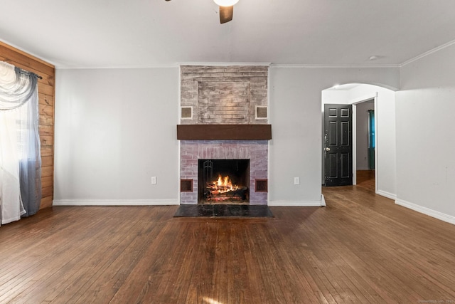 unfurnished living room with dark wood-type flooring, ceiling fan, ornamental molding, and a fireplace