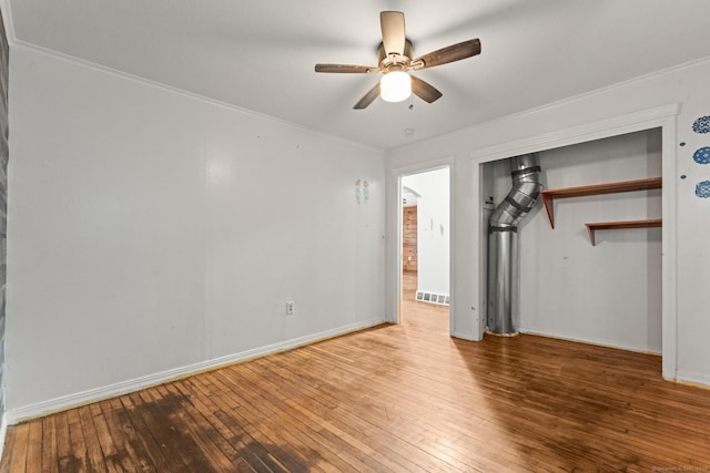 unfurnished bedroom featuring hardwood / wood-style flooring, ceiling fan, crown molding, and a closet