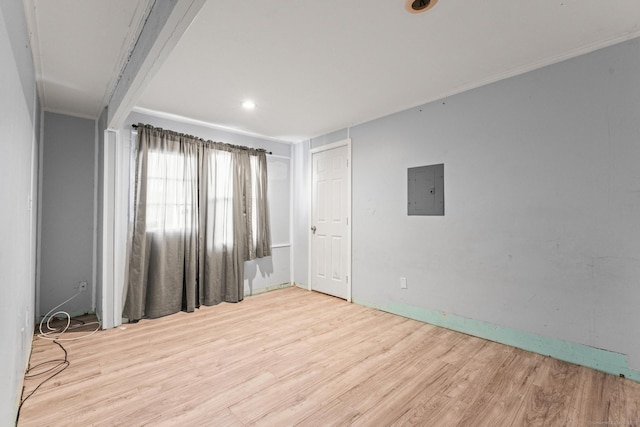 empty room featuring crown molding, electric panel, and light hardwood / wood-style floors